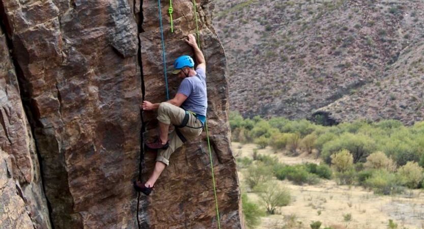 a person wearing rock climbing gear climbs a rock face in big bend texas